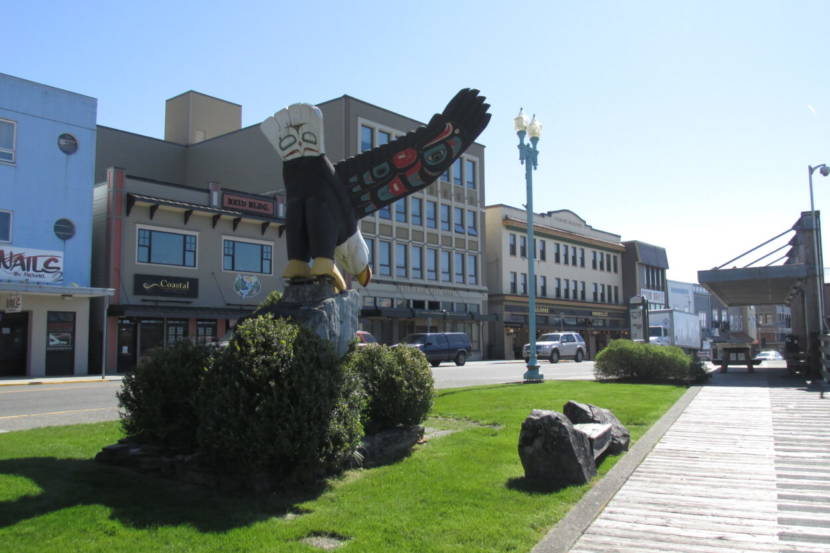 A huge wooden carving of an eagle perched on an actual rock on strip of grass in the middle of Ketchikan
