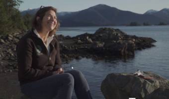 A woman sitting on rocks at the shore