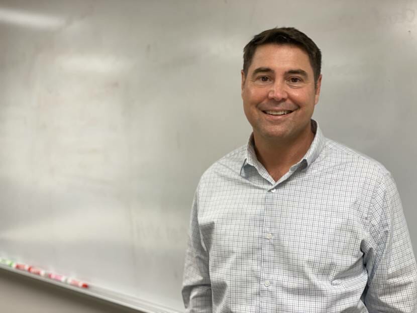 Shawn Arnold poses in front of a white board