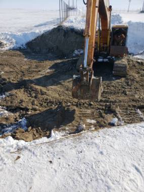 An excavator on top of newly moved dirt