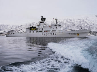 A Coast Guard cutter with snowy mountains in the background