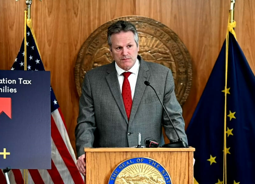 Gov. Dunleavy stands behind a lectern