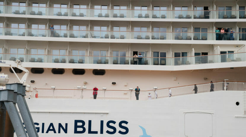 The side of a large cruise ship, with passengers visible on walkways