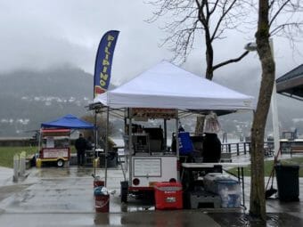 A food stand in Juneau's Marine Park is a collection of tables, grills and coolers under a white tent. A vertical banner says "Filipino Food" in blue, yellow and red -- the colors of the Philippines flag.