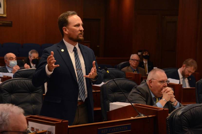 A lawmaker in a suit standing and speaking on the House floor