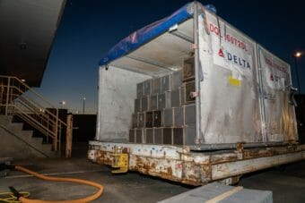 A large white container full of sliver crates on an airport tarmac