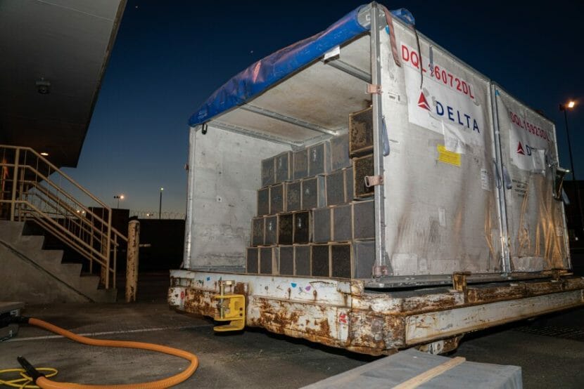 A large white container full of sliver crates on an airport tarmac