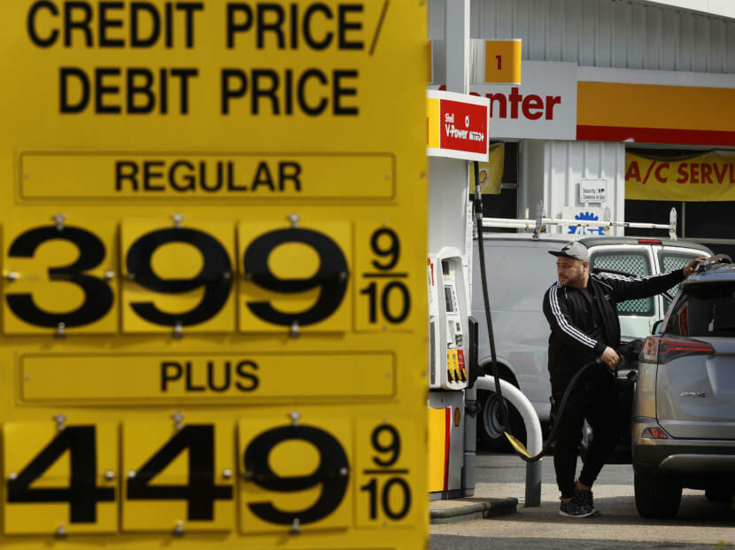 A man pumps gas by a sign advertising $4.50 gas