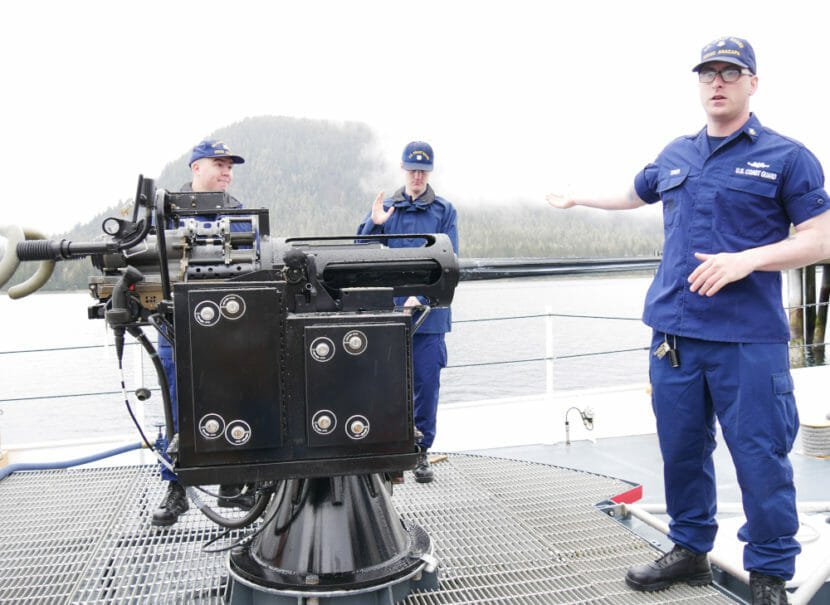 Men in uniform stand around a deck gun