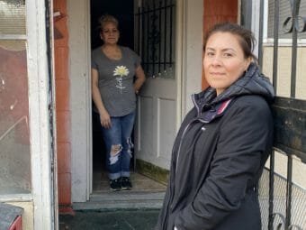 Two women stand at the entrance to a house