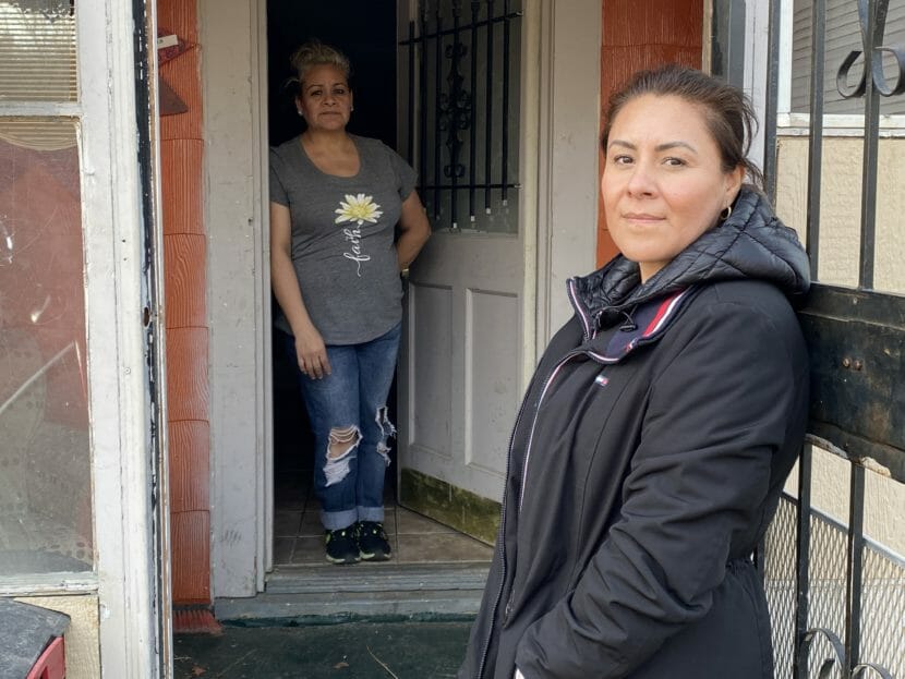 Two women stand at the entrance to a house