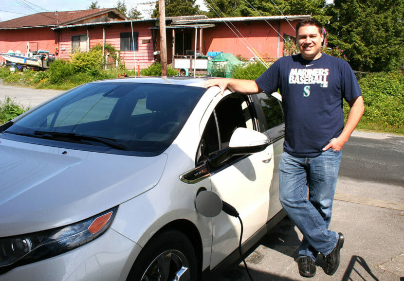 A man leans against a Chevy Volt