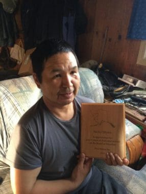 A man holding a plaque recognizing his service to Pilot Station