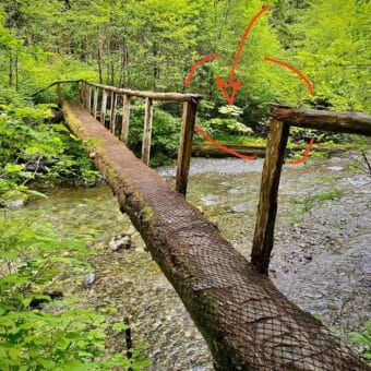 An image of a narrow footbridge over a stream. A section of railing is gone where the hiker fell through it.