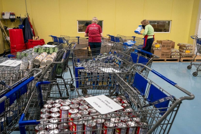 Two people in a warehouse filled with boxed and canned food