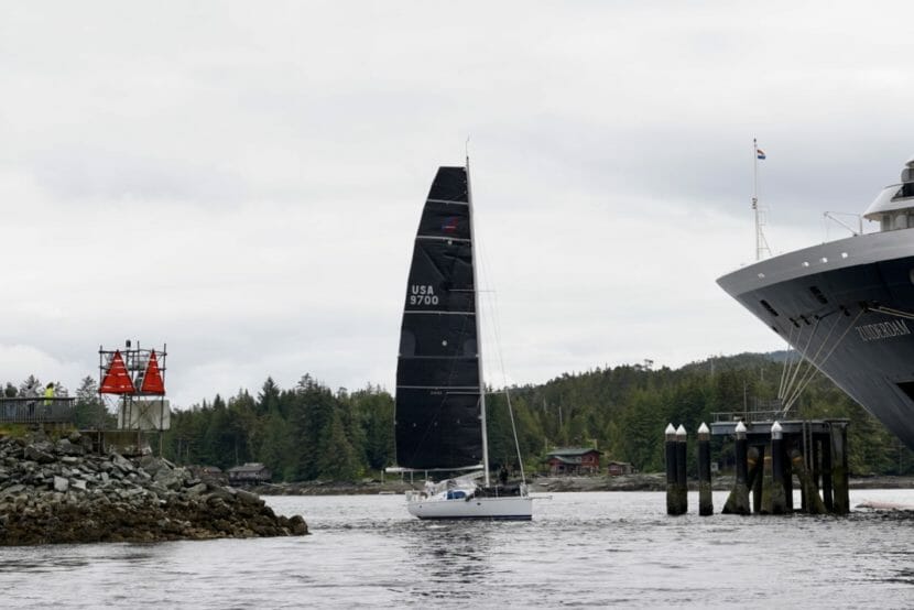 A sailboat slipping between shore and a cruise ship
