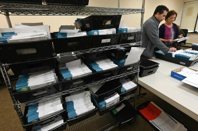 Two elections workers going through ballot envelopes.