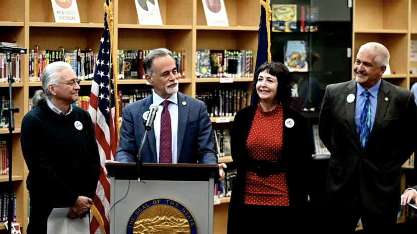 Four people stand behind a lectern set up in a library