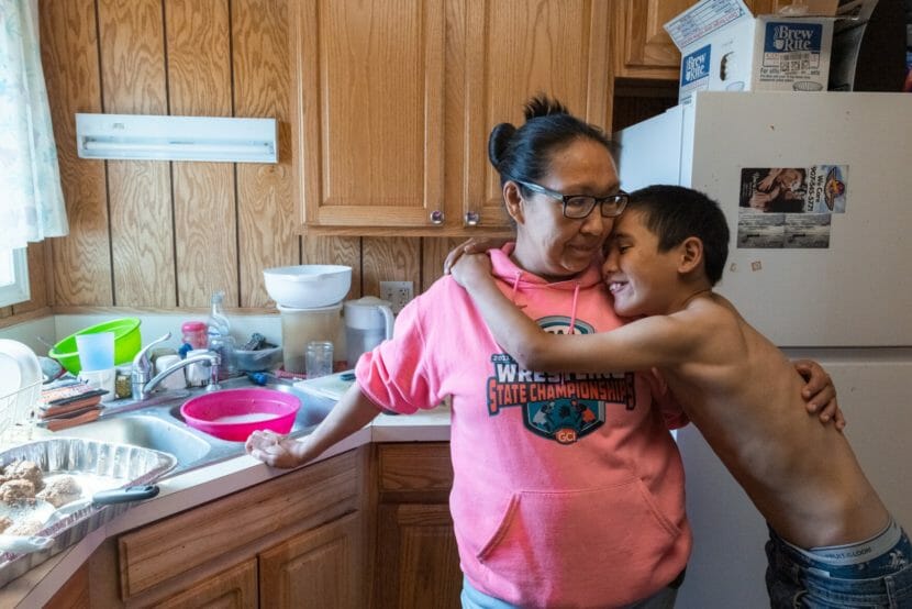 A boy hugs a woman by a kitchen counter