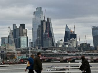 People walking across a bridge with skyscrapers in the background