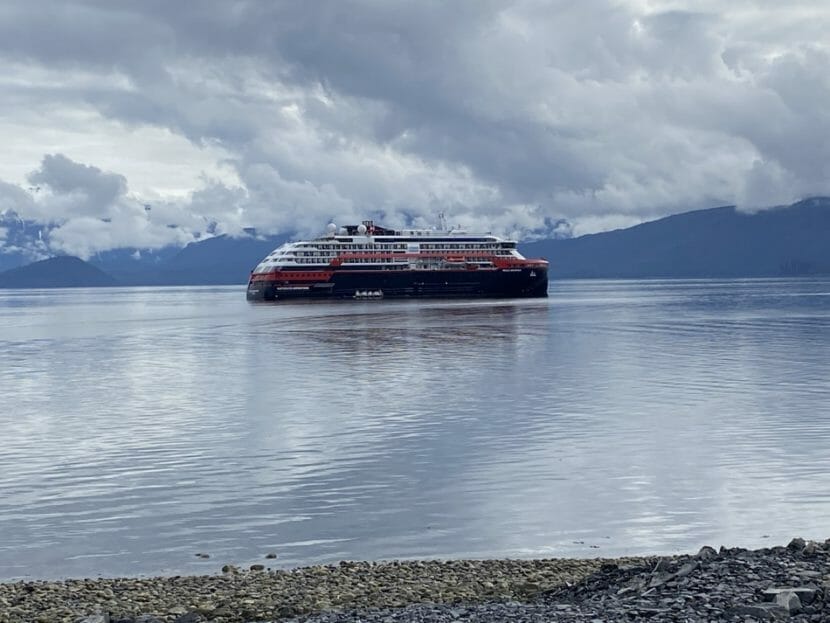 A cruise ship on calm waters with mountains behind it