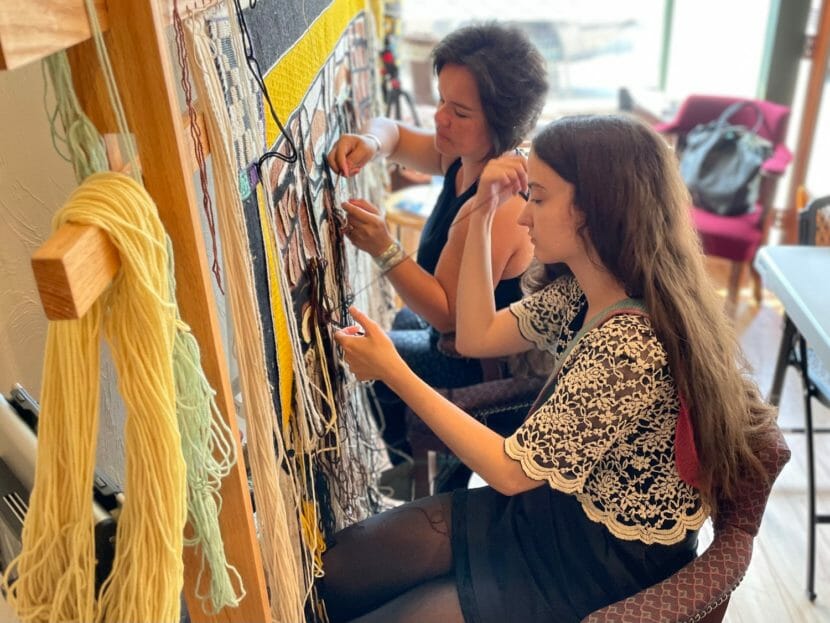 Two women working on weaving the same blanket