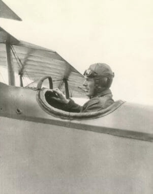 An old sepia-toned photo of a pilot in an open cockpit