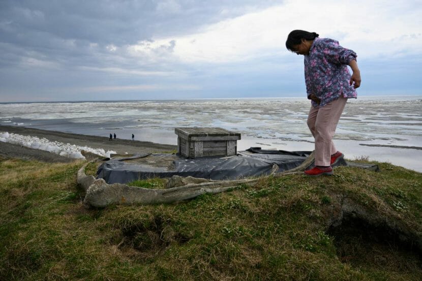 A woman stands on top of a bluff by the sea