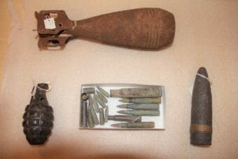A grenade, a box of bullets, and other unexploded munitions laid out on a table