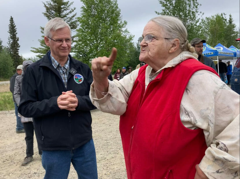An older woman raises her finger while talking to a state official