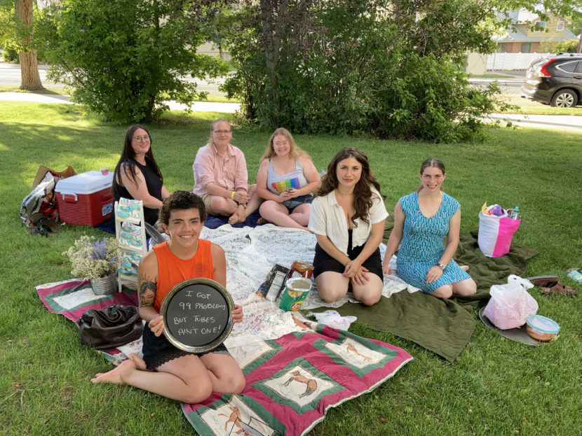 A group of people sitting on picnic blankets in a park 