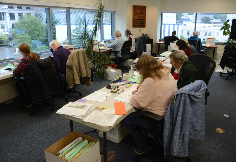 Rows of people seated at folding tables studying and marking sheets of paper