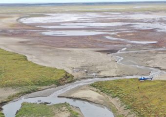 A helicopter sitting by a mostly dry lakebed