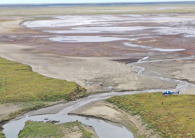 A helicopter sitting by a mostly dry lakebed