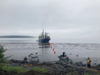 A ship leaving Unalaska dragging a heavy cable behind it