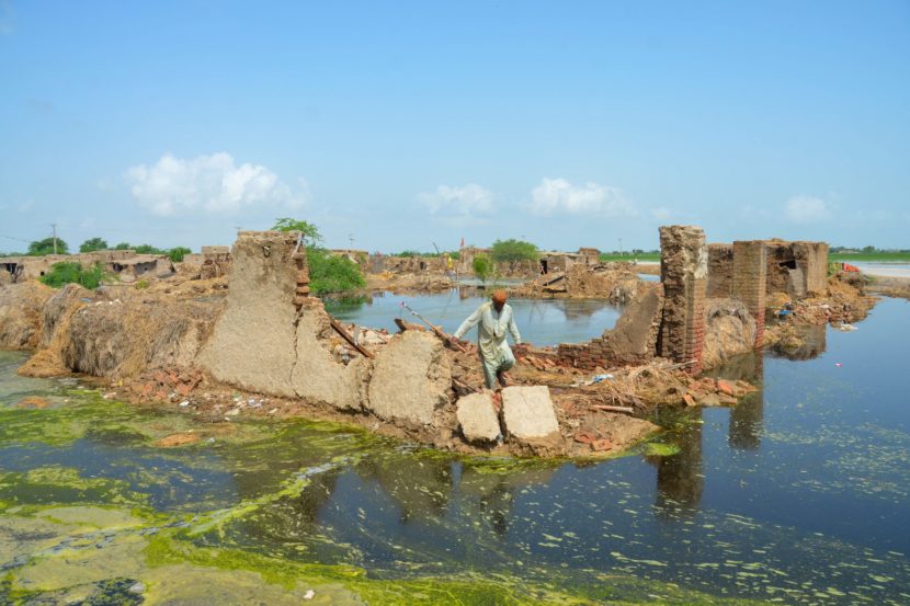 A man walks on the foundation of a ruined house surrounded by water