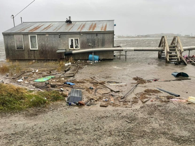 A house sits in floodwater surrounded by debris