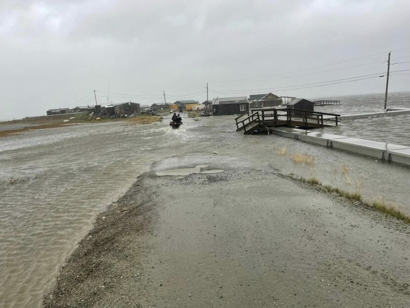 Two people on an ATV driving through floodwaters