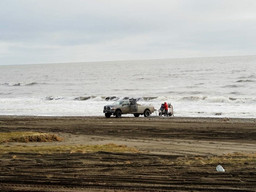 A pickup truck backed up to the water with a piece of mining equipment next to it