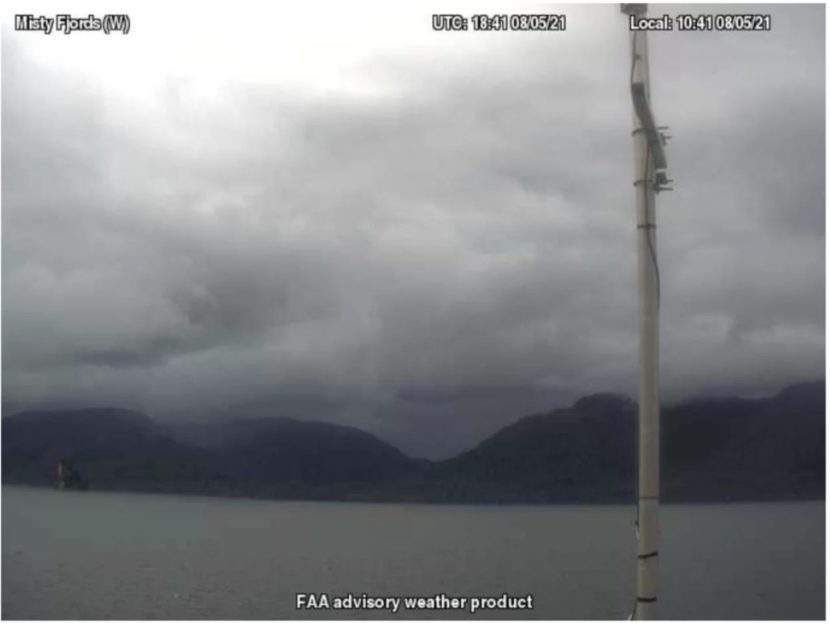 A view across a body of water showing hills with cloud cover obscuring their peaks