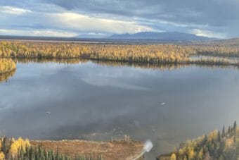 Trees in yellow fall colors surround a placid lake that has pieces of an airplane floating in it