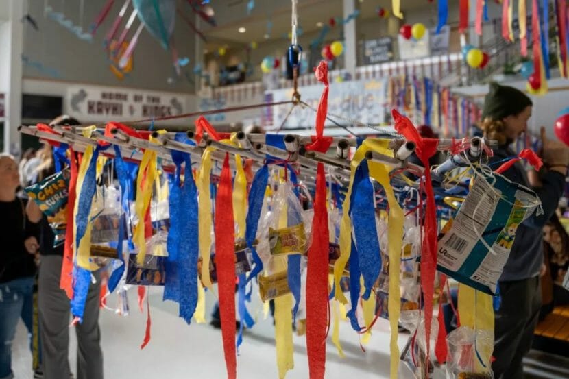 A colorful hanging frame with streamers and snacks hanging off of it