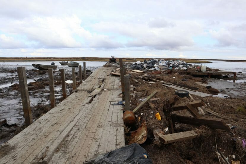 A wooden walkway across tundra strewn with debris