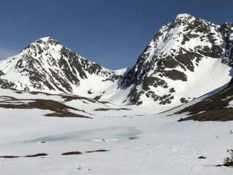 A pair of steep, treeless Chugach peaks, smeared with snow.