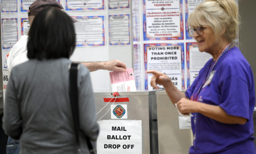 A voter dropping a ballot in a drop box