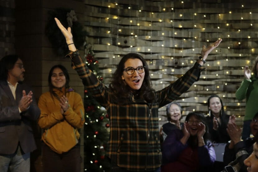 Mary Peltola holds up her arms as people applaud behind her.