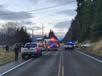 Emergency vehicles parked along a road by a steep hillside