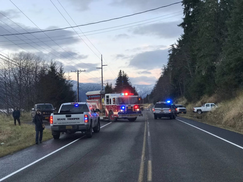 Emergency vehicles parked along a road by a steep hillside