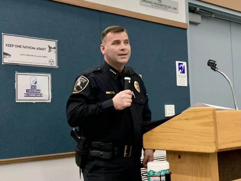 A man in a police uniform stands behind a lectern