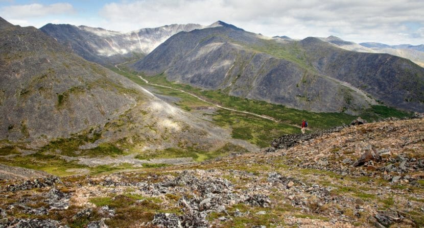 A lone hiker on a high hill overlooking a remote river valley.